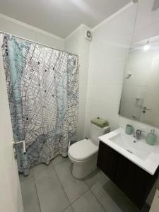 a bathroom with a toilet and a sink and a shower curtain at Dormitorio Cerro Cárcel Parque Cultural in Valparaíso