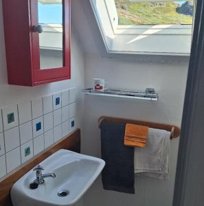 a bathroom with a sink and a window and towels at Isikkivik Cottage in Narsaq