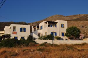 a white building with blue windows in front of a hill at Daira Apartments in Diakofti