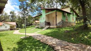 ein grünes und weißes Haus mit einem Rasenhof in der Unterkunft Águas Vivas Hotel Fazenda in Pirenópolis