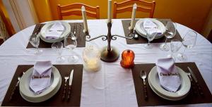 a table with a white table cloth with plates and wine glasses at A Beira da Cortella in Melón