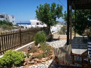 a garden with a wooden fence and a bench at Daira Apartments in Diakofti