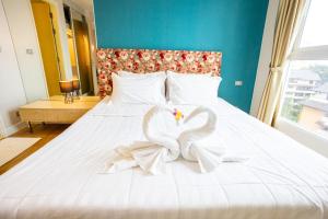 Grande Caribbean - 1 BR Apartment, 8th Floor #A815 في جنوب باتايا: بجعتان بيضاوان يجلسان على سرير