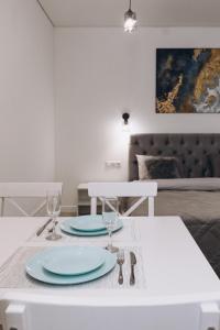 a white table with two plates and glasses on it at Apart Prokof'yeva in Sumy +8 photos