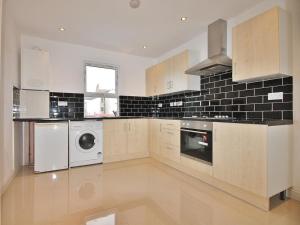 a kitchen with white cabinets and a washer and dryer at Thornton Heath in Thornton Heath