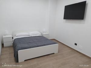 Un dormitorio blanco con una cama y un televisor de pantalla plana. en Maison Cleo, en Torre Annunziata