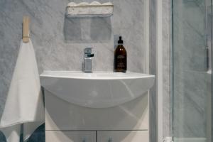 a white bathroom sink with a bottle of alcohol on it at Luxury seaside getaway Whitley Bay in Whitley Bay +9 photos