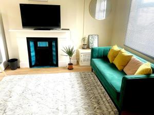 a living room with a green couch and a fireplace at Evo Green Gravesend 2 bed Apartment, 2 mins Station, Town Centre in Gravesend
