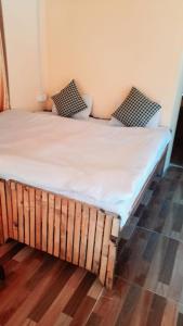 two twin beds in a room with wooden floors at Moksha By The River,Jibhi in Jibhi