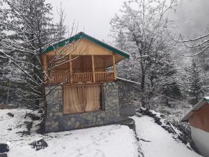 a cabin in the snow with a balcony at Moksha By The River,Jibhi in Jibhi