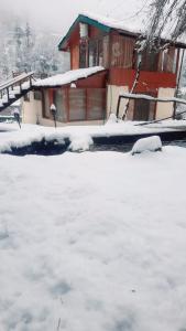 a snow covered yard in front of a house at Moksha By The River,Jibhi in Jibhi