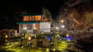 a building with lights in a garden at night at Moksha By The River,Jibhi in Jibhi
