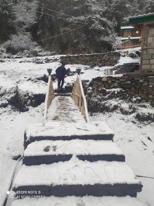 a man walking down a snow covered bridge at Moksha By The River,Jibhi in Jibhi