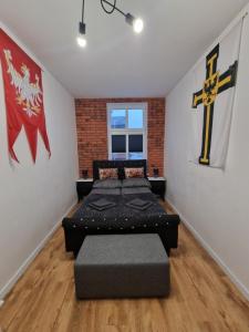 Cette chambre comprend 2 lits et une croix sur le mur. dans l'établissement Apartamenty Zakonne "Apartament Wielkiego Mistrza", à Malbork