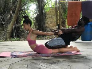 two people sitting on a mat doing yoga at Garden Lodge - Cape Three Points in Atinchin