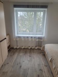 a bedroom with a large window and a wooden floor at Maironio Apartamentai in Radviliškis