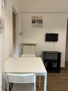 une table blanche et des chaises dans une pièce avec une télévision dans l'établissement A due passi dal mare, à Montesilvano