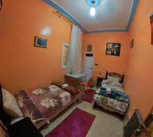 two beds in a room with orange walls at Maison d'hôtes de Zaida in Zeïda +8 photos