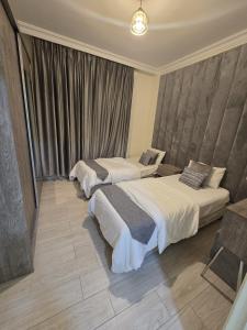 a hotel room with two beds and a window at Gardens Complex in Amman