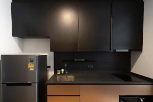 a kitchen with black cabinets and a stainless steel refrigerator at Edge Central Pattaya - Luxury 1 BR Apartment - 6th Floor #52 in Pattaya Central