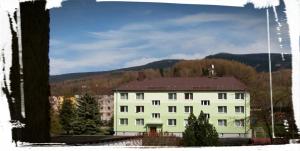 a large white building with a mountain in the background at Apartmán Loučná nad Desnou in Loučná nad Desnou