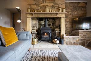 a living room with a stone fireplace and a couch at Cosy, tranquil, fully equipped & beautiful garden - Dene Cottage in Newham