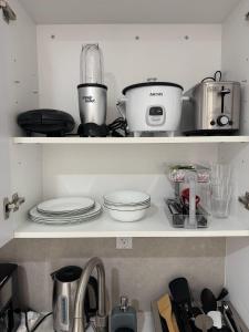 a kitchen shelf filled with pots and pans at Modern and cozy room in North Miami Beach