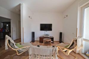 a living room with three chairs and a tv at Słoneczny Dom in Poddąbie