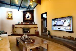 a living room with a couch and a tv on the wall at Nanshe MuXi Heritage Inn in Zhangjiajie