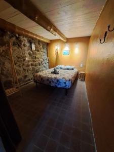 a bedroom with a bed in a room with a stone wall at La Maisonnette in Présailles