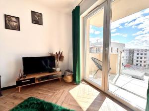 Una sala de estar con televisión y una gran ventana. en Ami Luxury Residence XII CENTRUM - możliwość REJSU ŁODZIĄ, en Iława
