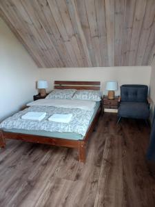 a bedroom with a bed and a blue chair at Nad Stawami in Białowieża