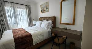 a bedroom with a bed and a mirror and a chair at Hotel Hibiscus POG in Port-Gentil