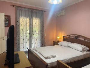 a bedroom with a bed and a television and a window at House Garden in Kalamoti in Kalamoti
