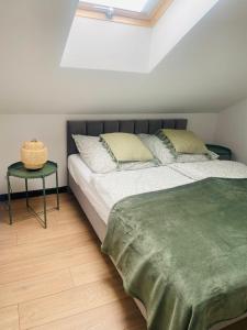 a bedroom with a bed with a green blanket and a table at Harmony House -Appartement Green in Kołczewo