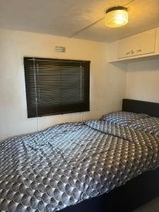 duże łóżko w pokoju z oknem w obiekcie stacaravan Dunepark w mieście Oostduinkerke