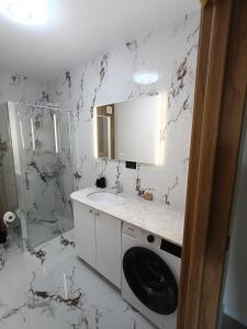 a white bathroom with a sink and a washing machine at NXN Airportstay in Cluj-Napoca