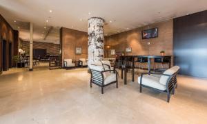 een lobby met stoelen en een tafel en een tv bij Hotel Mercader in Madrid