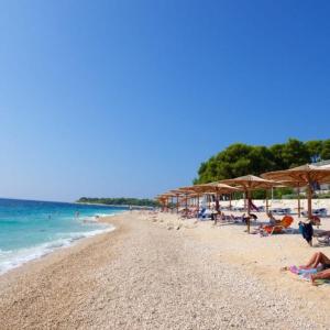 a beach with umbrellas and people laying on the beach at Villa Luketini Dvori, Primošten in Kruševo