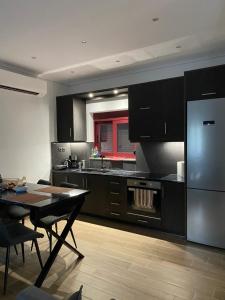 a kitchen with black cabinets and a table and a refrigerator at Mountain View Apartment in Pramanta