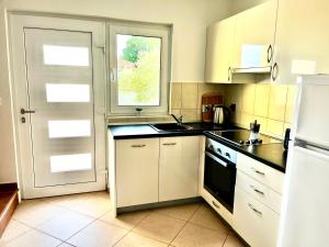 eine Küche mit weißen Schränken und einer Spüle und einem Fenster in der Unterkunft Dija Riva 1 in Vabriga