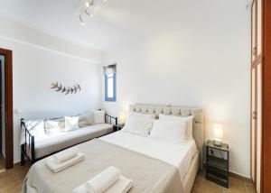 a white bedroom with a bed and a couch at A L'AISE STUDIOs in Apolpaina