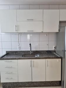 una cucina con mobili bianchi e un lavandino di Apto versátio trabalho e lazer a Cuiabá