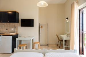 a bedroom with a bed and a kitchen with a table at Kamini Apartments in Kavos