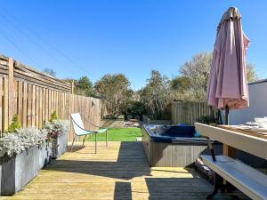 a patio with an umbrella and a chair and a table at Hydrangea House - Luxury Hideaway with Hot Tub - Sleeps 10 - Pets Welcome! in Hythe