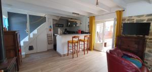 een woonkamer met een keuken en een bar met krukken bij Ty Kichen Mor - campagne - wifi in Crozon