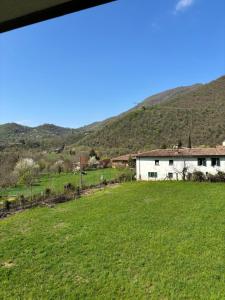 a house in a field with a hill in the background at BiancoGelso b&b Vegan in Gardone Riviera