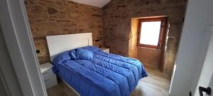 a bedroom with a bed with a blue comforter and a window at Casa Cuchariños Louro in Louro