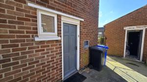 a brick building with a door and a trash can at Kabaka - Comfy Birley 3 Bedroom Home in Frecheville