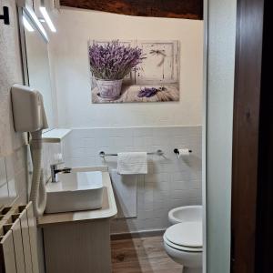 a bathroom with a sink and a toilet and a painting at casa vacanze nel Chianti il Granaio in Castellina in Chianti +19 photos